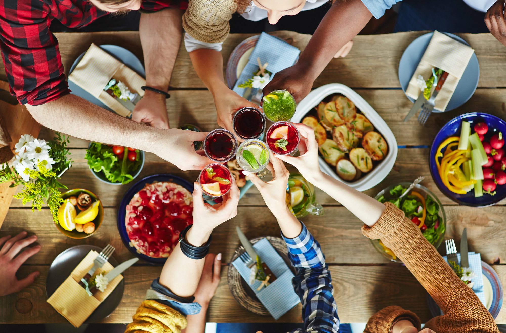 Un groupe d'amis trinquant avec des cocktails colorés autour d'un brunch gourmand composé de salades, gratins et desserts. Découvrez les meilleures boissons pour accompagner votre brunch et sublimer vos moments conviviaux.