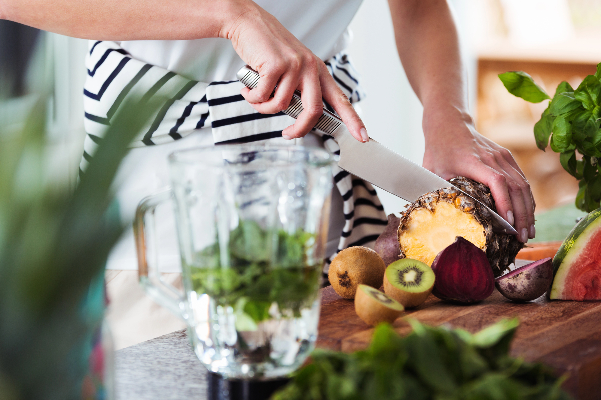 Préparation d’un smoothie frais et sain à base d’ananas, kiwi et légumes verts, parfait pour un petit déjeuner nutritif. Les bienfaits d’un bon petit déjeuner riche en fibres et en vitamines permettent de booster l’organisme dès le matin.