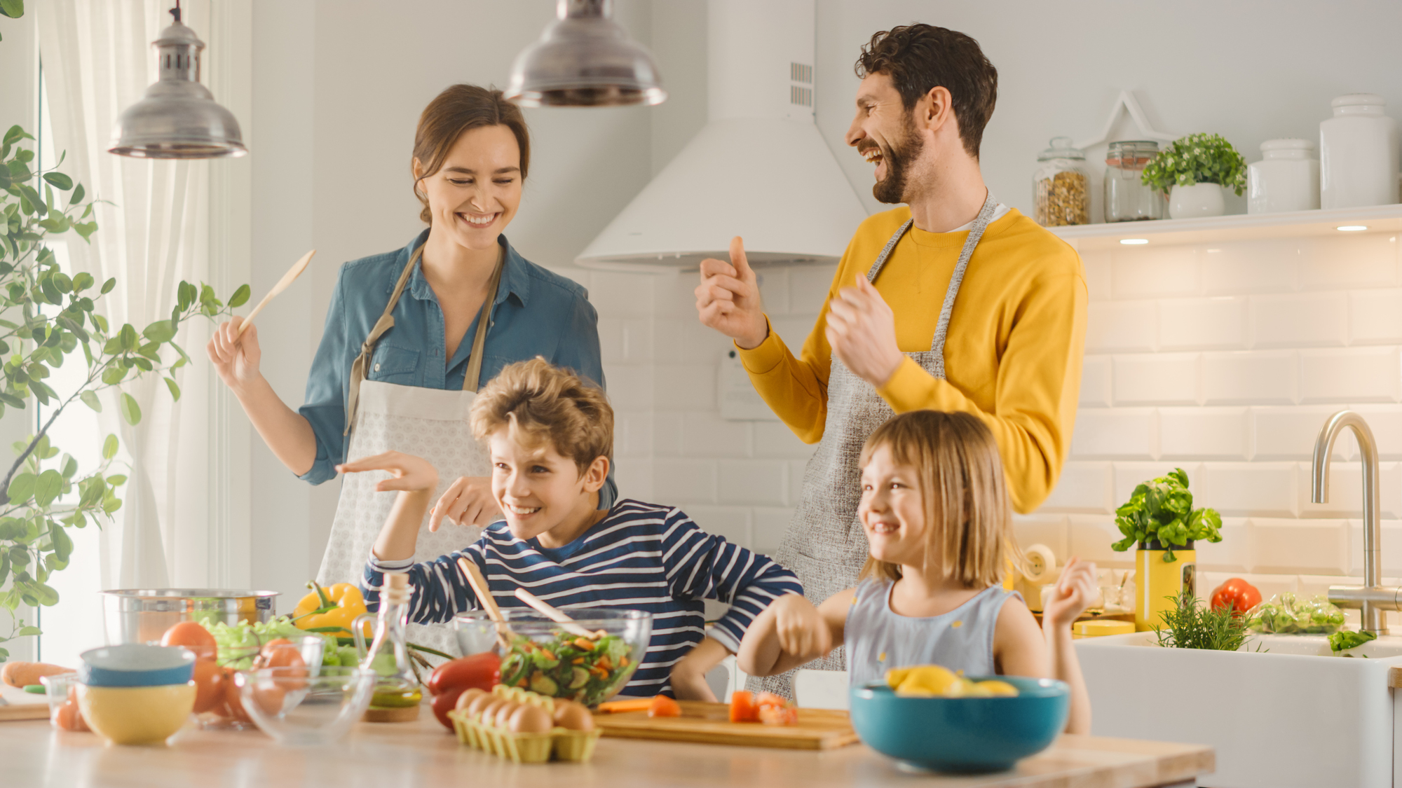 Une famille souriante cuisine ensemble dans une cuisine moderne et lumineuse, préparant un brunch sain et équilibré. Pourquoi le brunch en famille est une tradition à adopter ? Parce qu’il renforce les liens et encourage une alimentation conviviale.