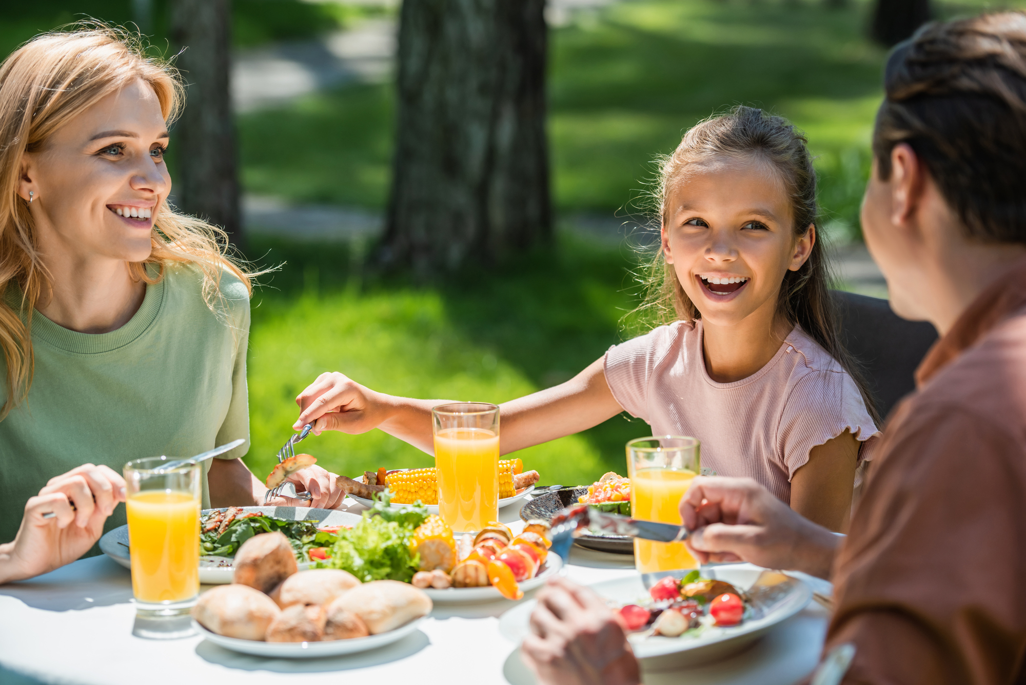 Une famille partage un brunch en plein air, savourant des plats colorés sous un soleil radieux. Pourquoi le brunch en famille est une tradition à adopter ? Il permet de profiter d’un moment de qualité en plein air avec des repas équilibrés.