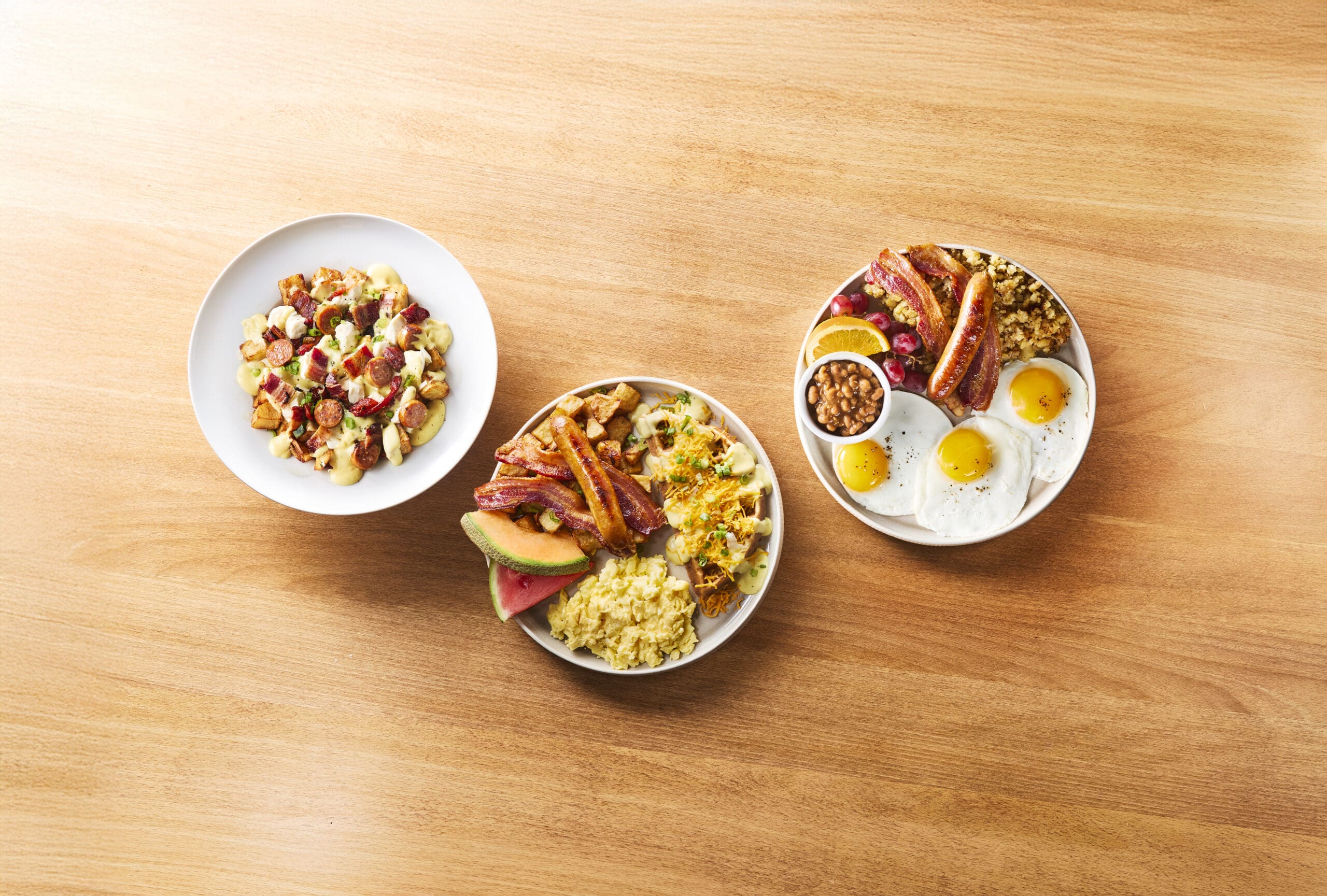 Trois nouvelles assiettes de brunch « Allô mon Coco » composées de tranches épaisses de bacon, de saucisses artisanales, d'œufs, de gaufres et de pommes de terre