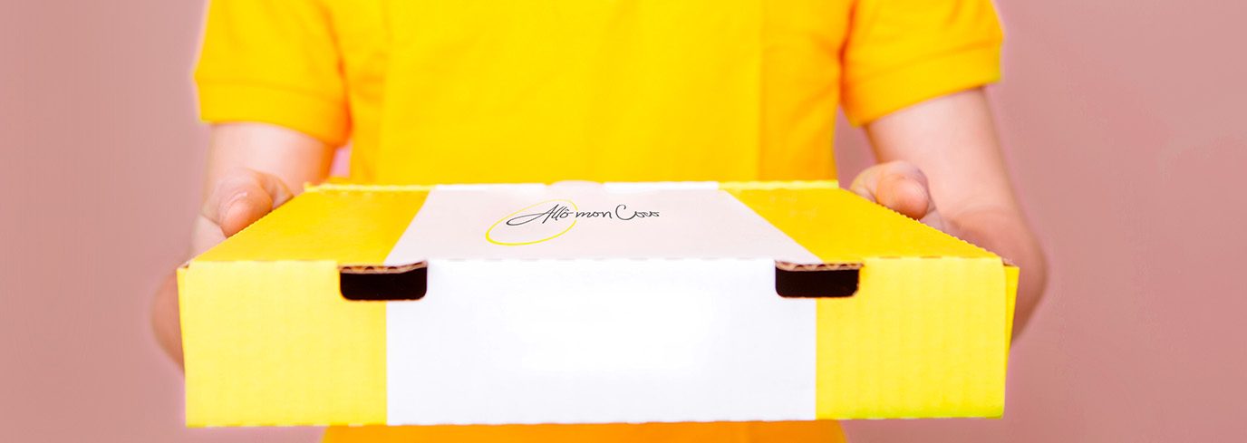 brunch-en-semaine Employé en polo jaune tenant une boîte de brunch à emporter Allô mon Coco