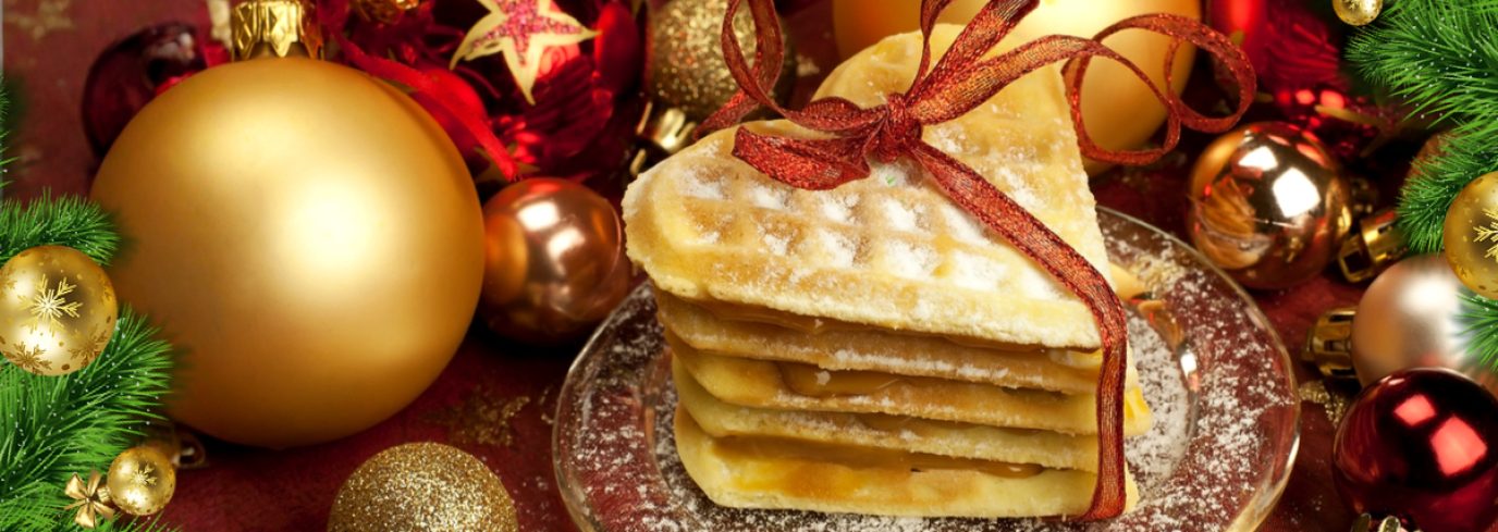 Pile de gaufres garnies et nouées d’un ruban rouge, saupoudrées de sucre, entourées de décorations de Noël festives, évoquant un brunch chaleureux pour un party de bureau.
